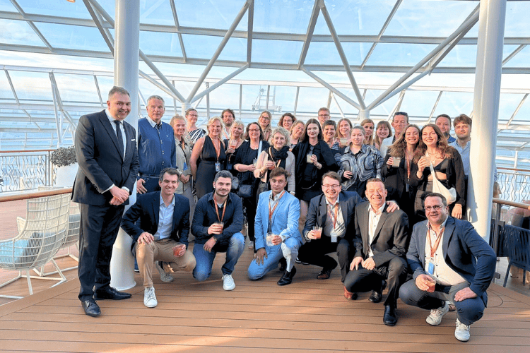 Eine Gruppe von Menschen posiert auf einem Schiffsdeck mit einem Glasdach über dem Kopf bei dem Seminar@Sea von Royal Caribbean